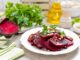 Rote Beete auf einem weißen Teller, daneben Olivenöl und Gemüse