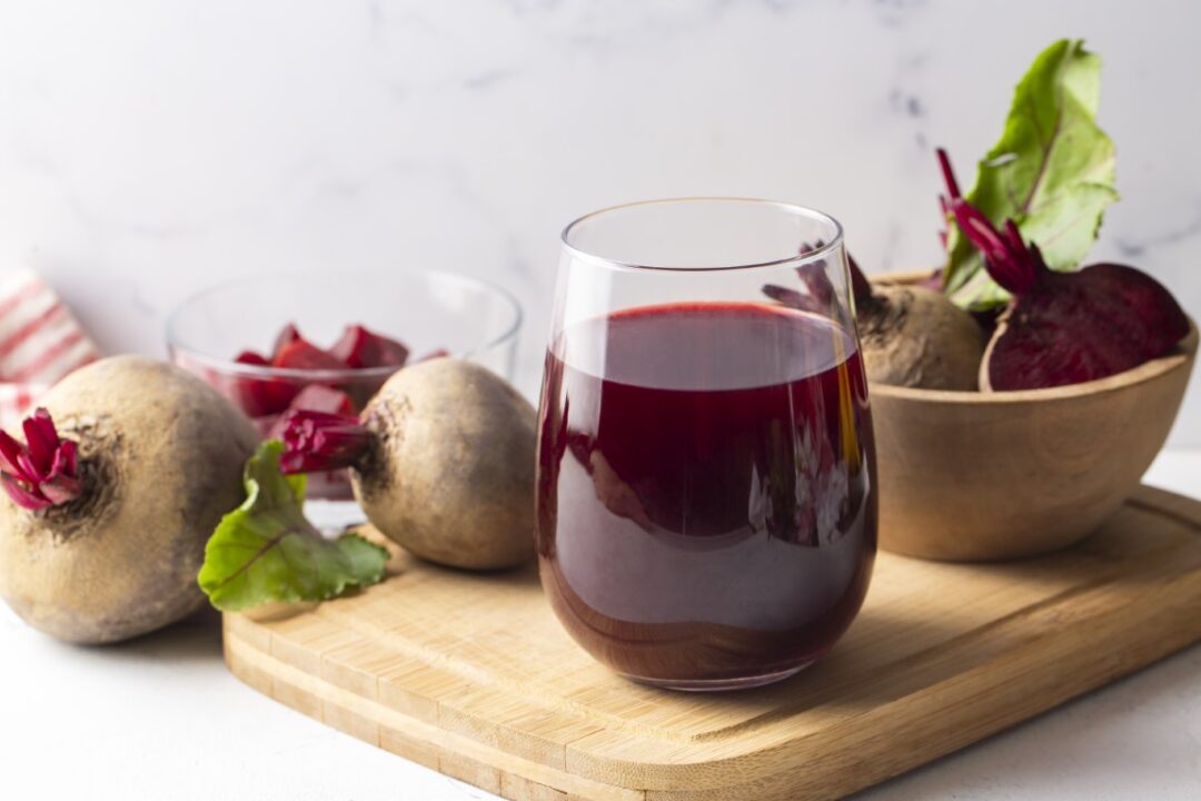 Flas mit frischem Rote Bete Saft, auf einem Brett mit frischem Gemüse.