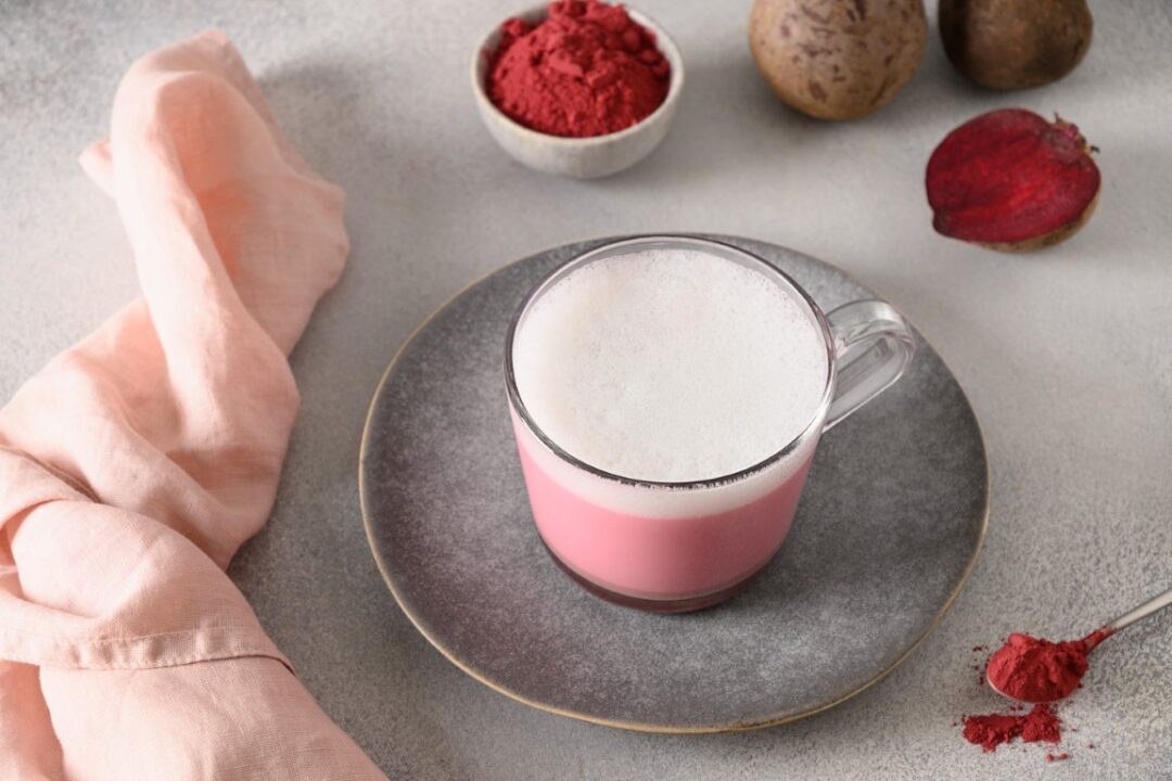 Pink-Latte auf einem grauen Teller, daneben aufgeschnittene Rote Bete