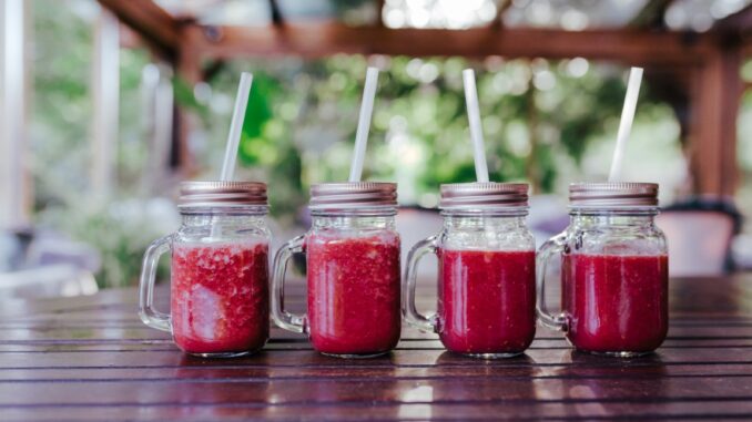 close up view of healthy juice in small jars on table. Made of w Rote Bete-Saft in kleinen Flaschen mit Strohhalm