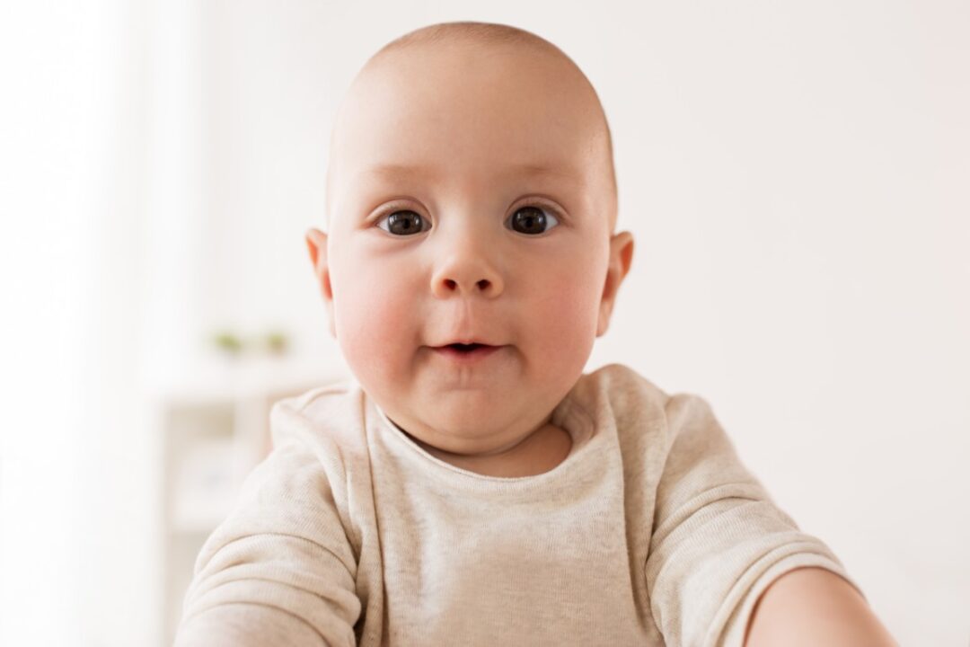 Baby lächelt neugierig in die Kamera
